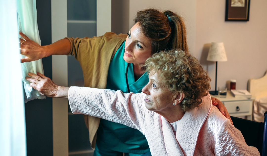 Older white female with younger white female support staff looking out window.